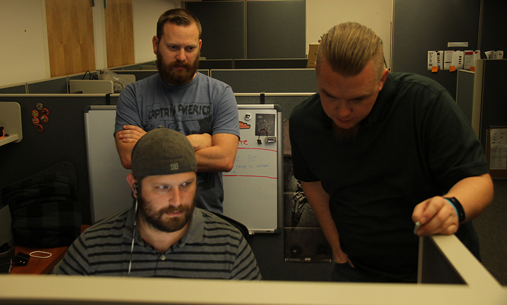 Employees standing over a computer